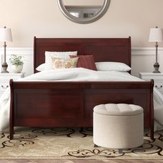 a bedroom with a bed, ottoman and round mirror on the wall above it's headboard