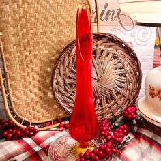 a red vase sitting on top of a table next to a basket and other items