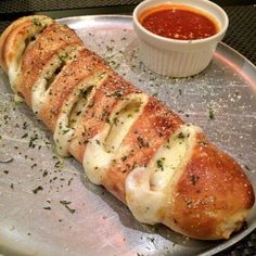 a piece of bread with cheese and sauce on a metal plate next to a bowl