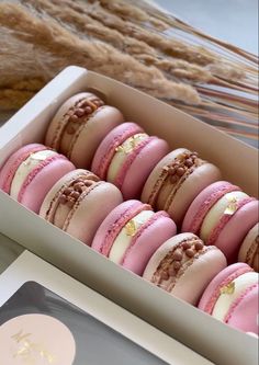 a box filled with pink and white macaroons sitting on top of a table