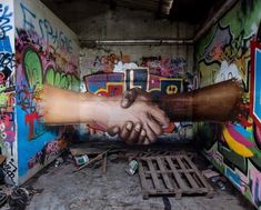 two hands reaching for each other in front of graffiti covered walls