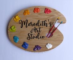 a wooden sign that says,'meredith's art studio'surrounded by colorful crayons and paintbrushes