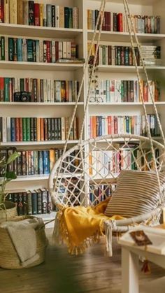 a white hanging chair in front of a book shelf filled with books