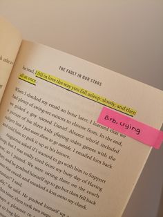 an open book with a pink sticky note attached to the front of it's page