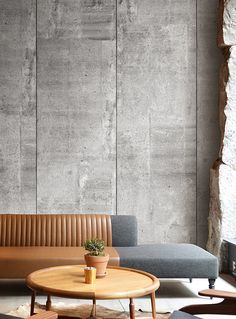 a couch and table in front of a concrete wall with an advertise on it