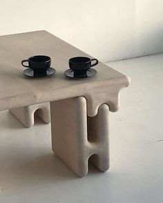 two coffee cups sit on top of a table made out of concrete blocks with matching plates