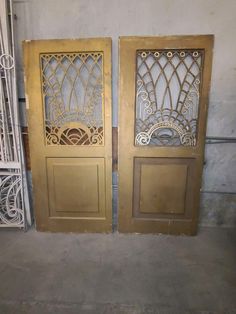 two gold doors with intricate designs on them in an empty room next to each other