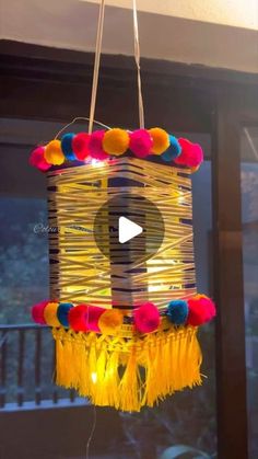 a bird house made out of yarn with lights hanging from it's sides and colorful pom - poms around the edges