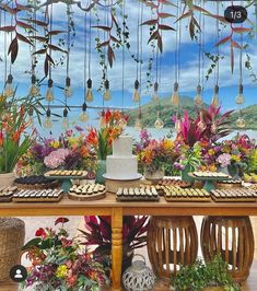 a table topped with lots of different types of cakes and cupcakes next to flowers