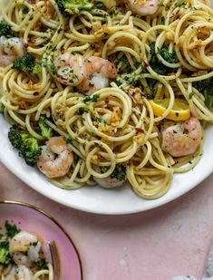 pasta with shrimp and broccoli in a white bowl on a pink tablecloth