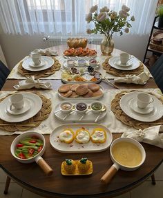 a table set with plates, cups and bowls filled with food on top of it