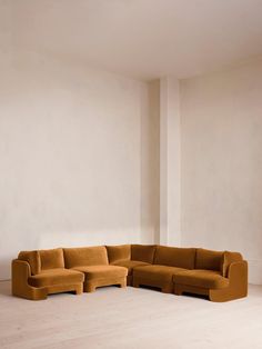 a large sectional couch sitting on top of a hard wood floor next to a white wall