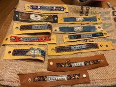 several pairs of leather wristbands are laid out on a piece of burlock