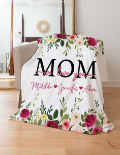 a blanket that says mom with flowers on it in front of a chair and mirror