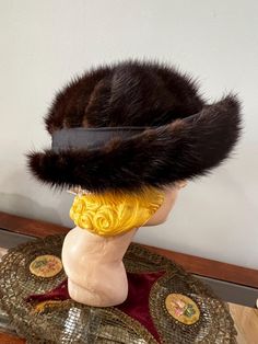 Vintage 1960's mink hat. Brown mink tails set on a brown felt harden form  in a pineheel pattern on the crown. It has turned up brim with fur attached to stiffened brim. There is a dark brown fabric band all around the base of the brim. Inside is unlined with a grosgrain sweatband. A union label is hanging on by a thread.  Measurements -  inches across and inches wide and stands inches high. Opening is  Shown on head form that is  Condition is very good. Hanging On By A Thread, Dark Brown Fabric, Brown Fabric, Vintage 1960s, The Crown, Caps Hats, Dark Brown, Accessories Hats, Beauty Book