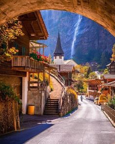 an arch leading into a village with mountains in the background