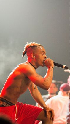 a man with dreadlocks on his head singing into a microphone at a concert