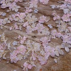 pink and white flowers are on the ground next to a piece of fabric that has been sequinized onto it