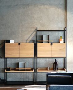 a living room filled with furniture next to a wall mounted shelf on top of a cement wall