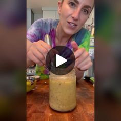 a woman is making a smoothie in a glass jar with a straw and spoon