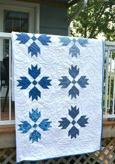 a blue and white quilt hanging on the side of a house