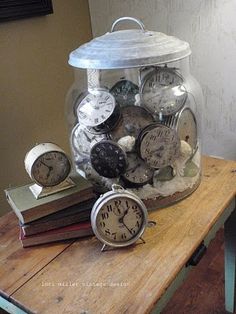 a jar filled with lots of different types of clocks on top of a wooden table