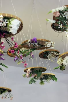 several hanging baskets filled with flowers and greenery