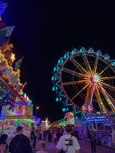 people are walking around an amusement park at night