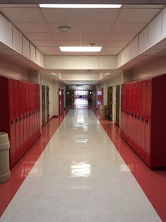 an empty hallway with red and white lockers