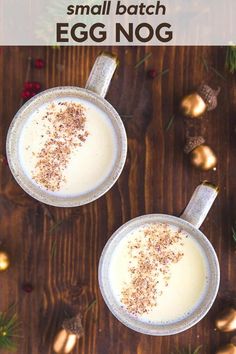 two mugs filled with milk and topped with cinnamon sprinkles on a wooden table