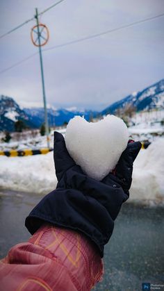 someone is holding a heart shaped snowball in their hand