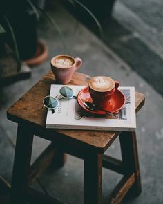 two cups of coffee sit on top of a magazine