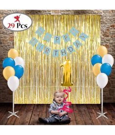 a baby sitting on the floor in front of balloons and streamers for a birthday party