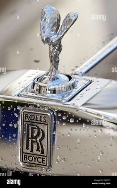 rolls royce emblem on the front of a rolls royce car in raindrops - stock image