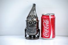 a metal robot next to a coca cola can