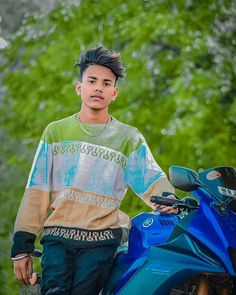 a young man standing next to a blue motorcycle