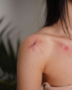 a woman's shoulder with a small dragonfly tattoo on her left arm and chest