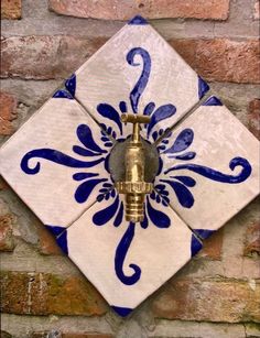 a blue and white tile with a golden faucet on it's side