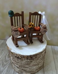 two wooden chairs sitting on top of a tree stump with pumpkins and sunflowers