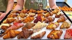 there are many croissants and pastries on the tray in this display