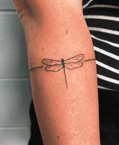 a woman's arm with a dragonfly tattoo on the left side of her arm