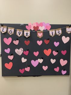 a bulletin board with hearts on it and the words love is spelled in small letters