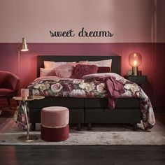 a bedroom with pink walls and black bed in the center, two chairs on either side