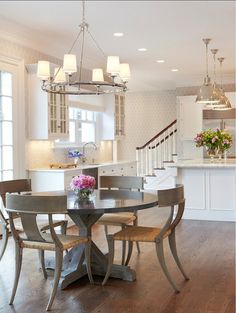 a dining room table with four chairs and a chandelier hanging from the ceiling