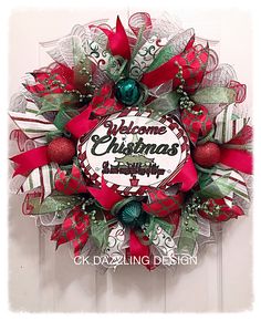 a red and green christmas wreath hanging on a door with the words welcome christmas to everyone