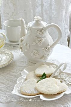 some cookies are on a plate near a tea pot