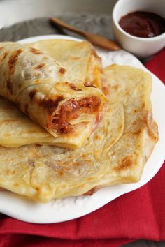 two quesadillas stacked on top of each other on a white plate with red table cloth