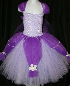 a purple and white tutule dress with flowers on the bottom, sitting on a mannequin