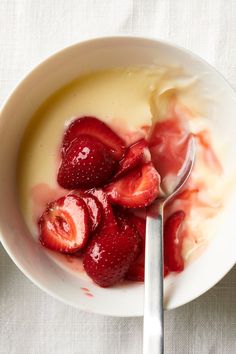 a bowl filled with yogurt and strawberries on top of a white table