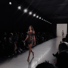 a woman walking down a runway in front of a crowd